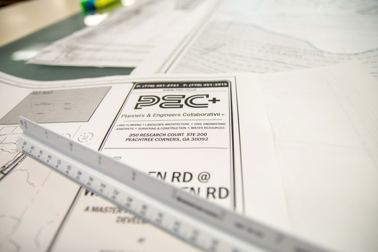 Architectural blueprints with a ruler and pen on a table showing plans from Planners & Engineers Collaborative.