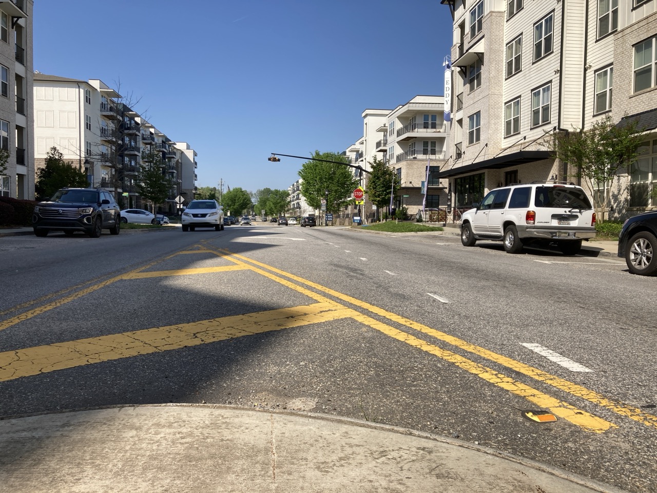 Long paved road with orange construction barrels on both sides under a partly cloudy blue sky showing PEC service Roadway Design.