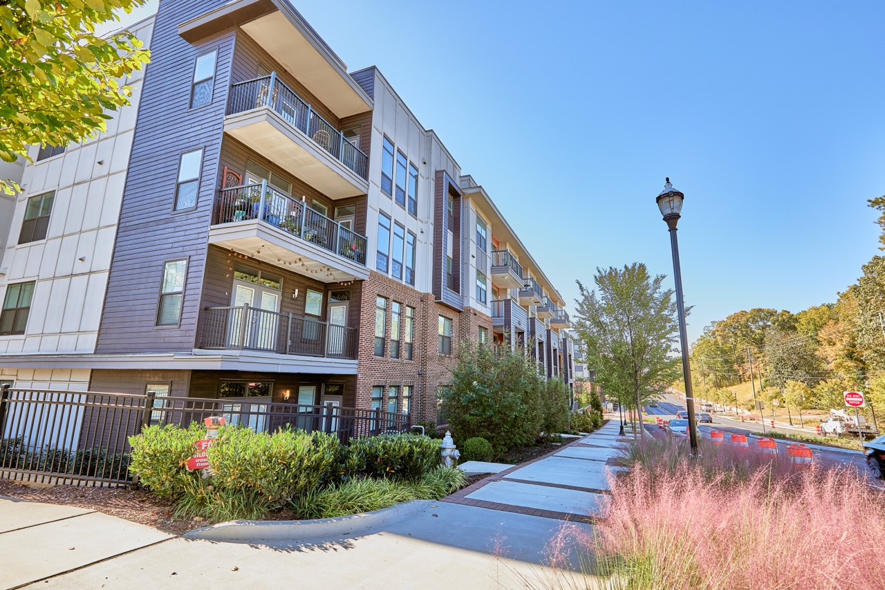 Exterior view of Sienna Apartments showing multi-story residential building with balconies along a sidewalk.