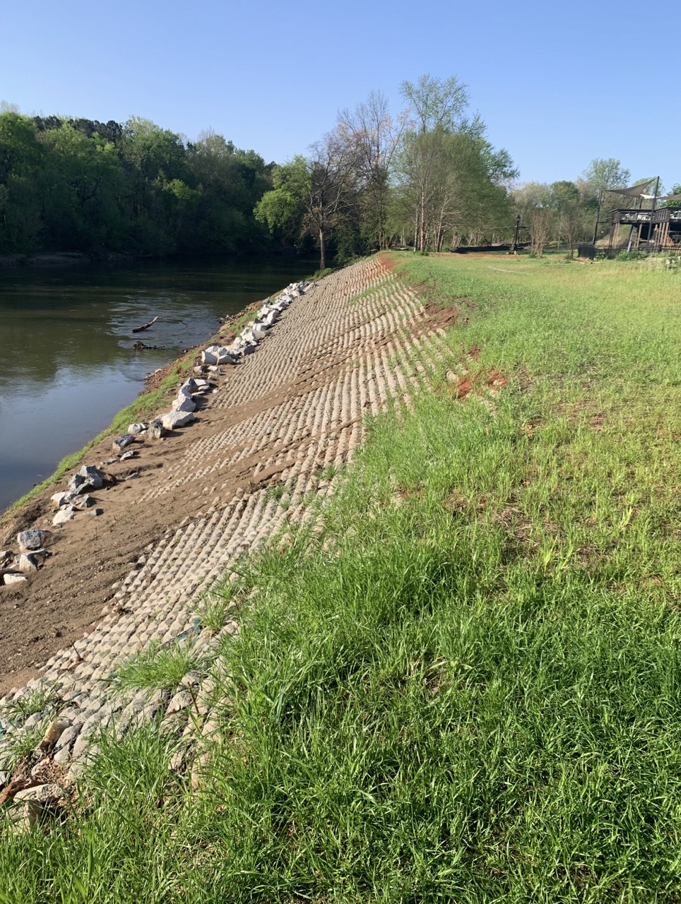 Stabilized riverbank along the Chattahoochee River showing streambank restoration with reinforced soil and rock edging.