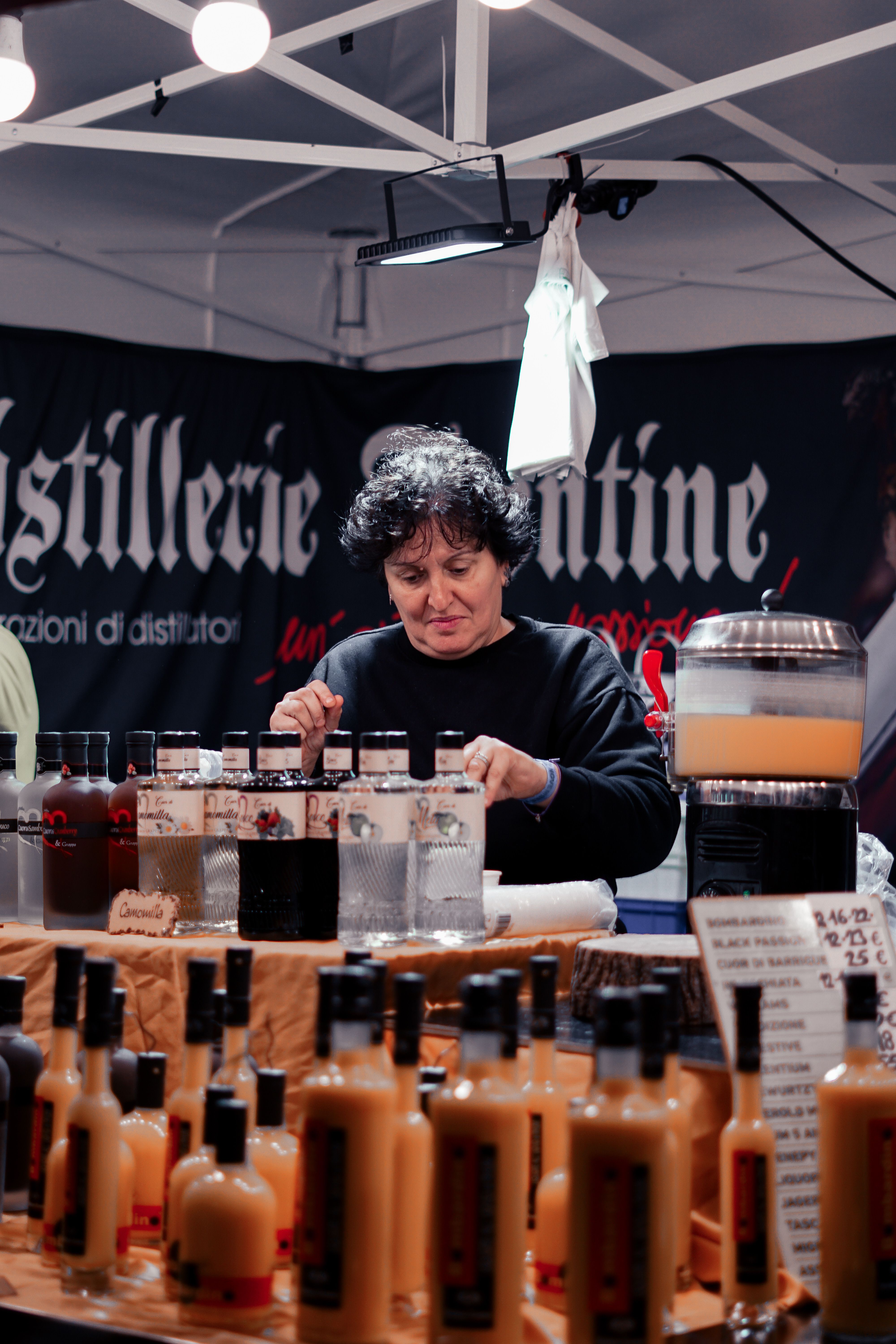 Woman arranging bottled drinks at a small beverage market stall