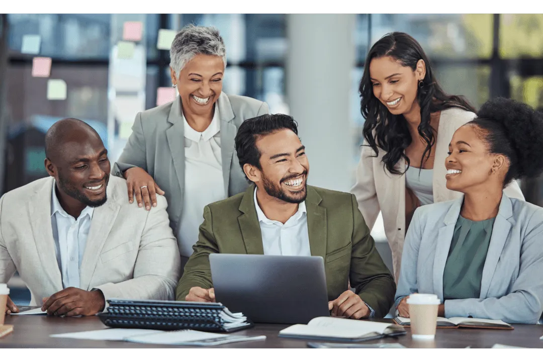 A group of multigenerational workers interact and look at a laptop computer.