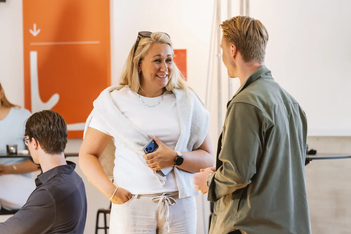 Dame som prater og smiler til en mann på konferanse
