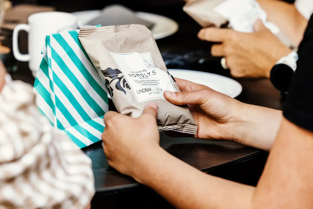 Hender som holder på en gavepakke og kaffe