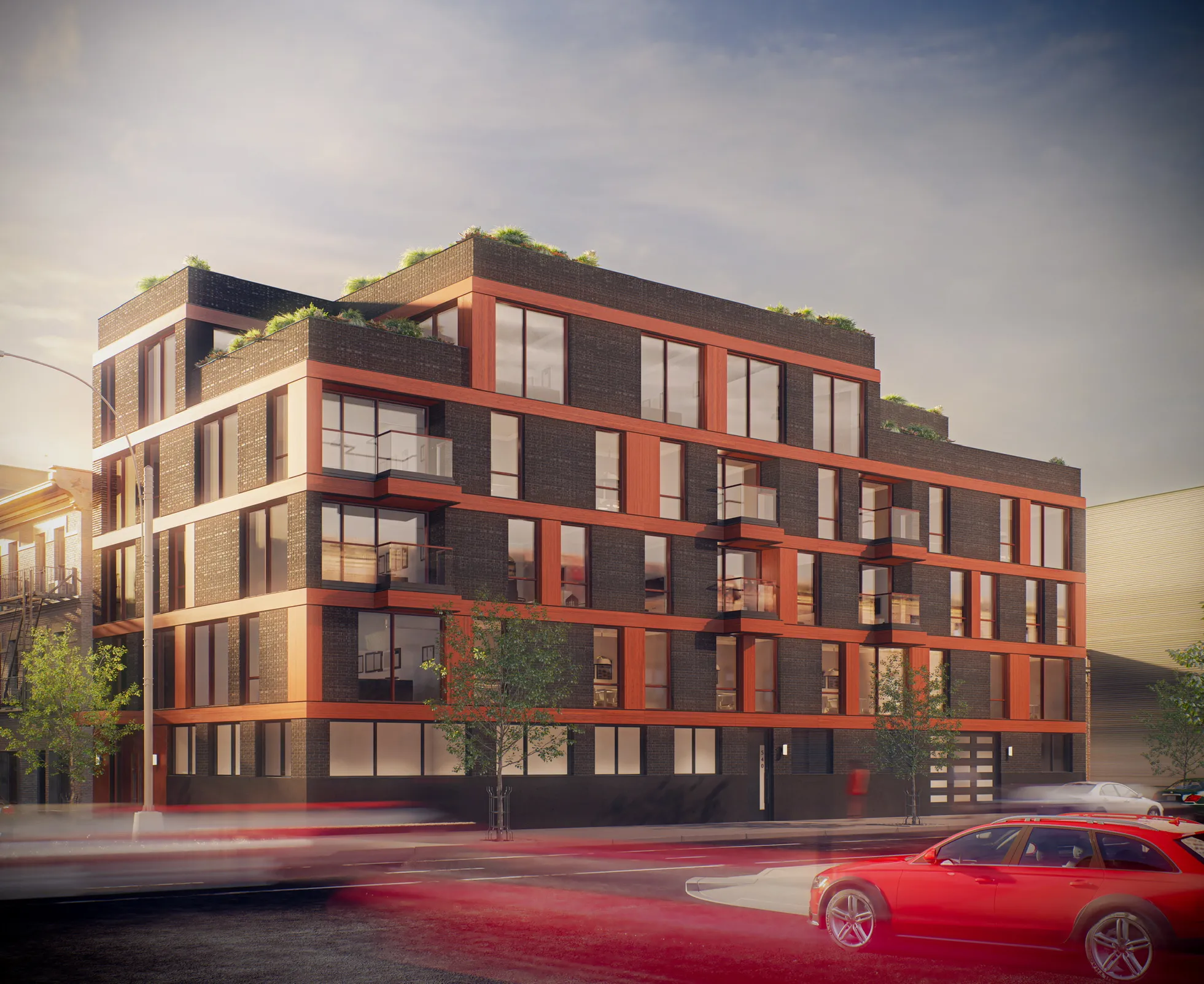 Modern four-story apartment building with dark brick and red trim, multiple balconies, rooftop greenery, and a red car parked nearby.
