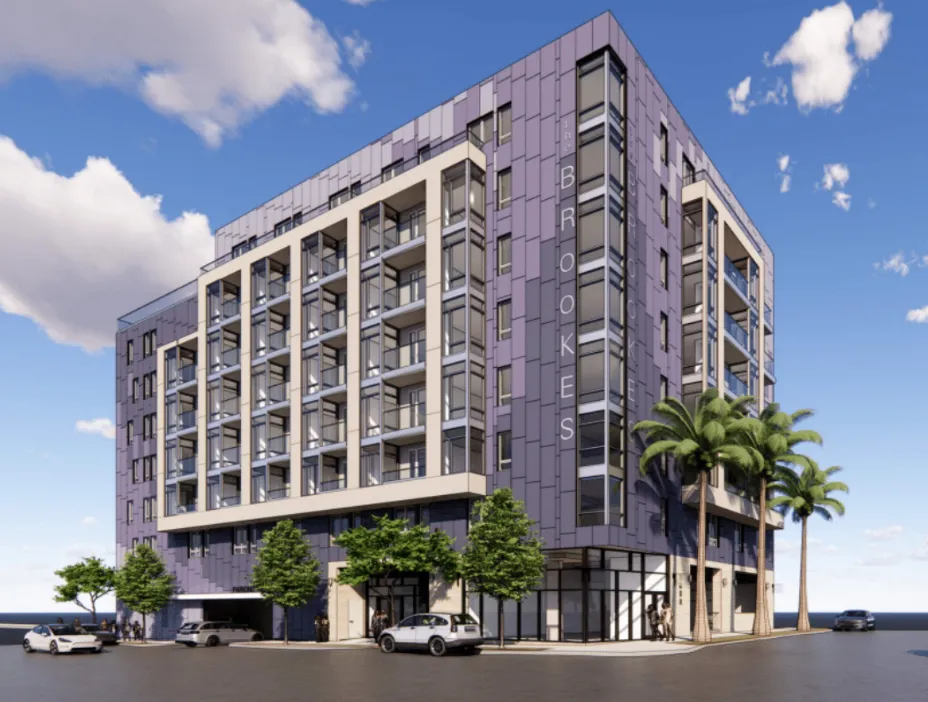 Modern six-story apartment building named The Brookes with balconies and palm trees on a sunny day.