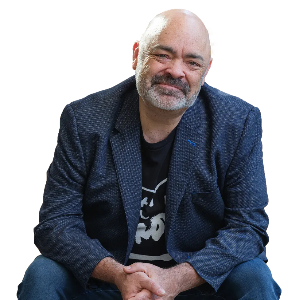 Rob Smith smiling, seated while leaning forward with arms resting on his knees.