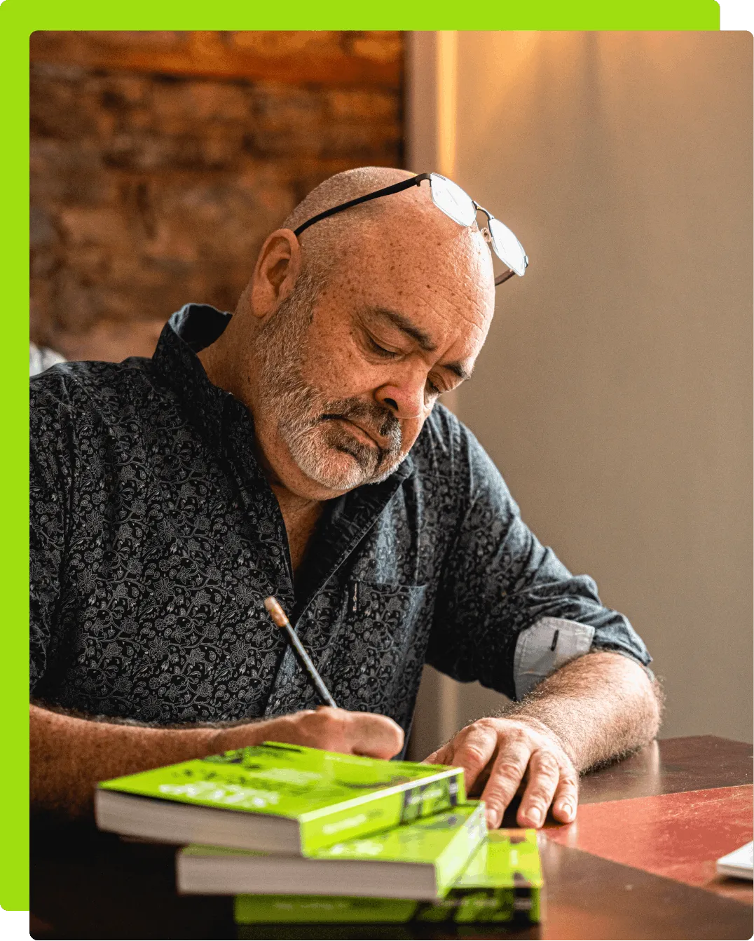Rob Smith sitting at a desk, signing copies of his book 'Stop Looking for Zebras'.