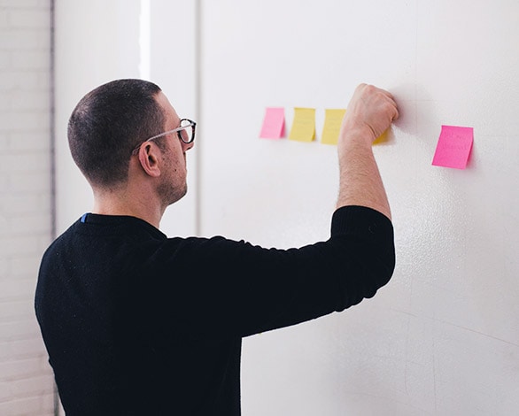 picture of a man arranging sticky notes on a white board