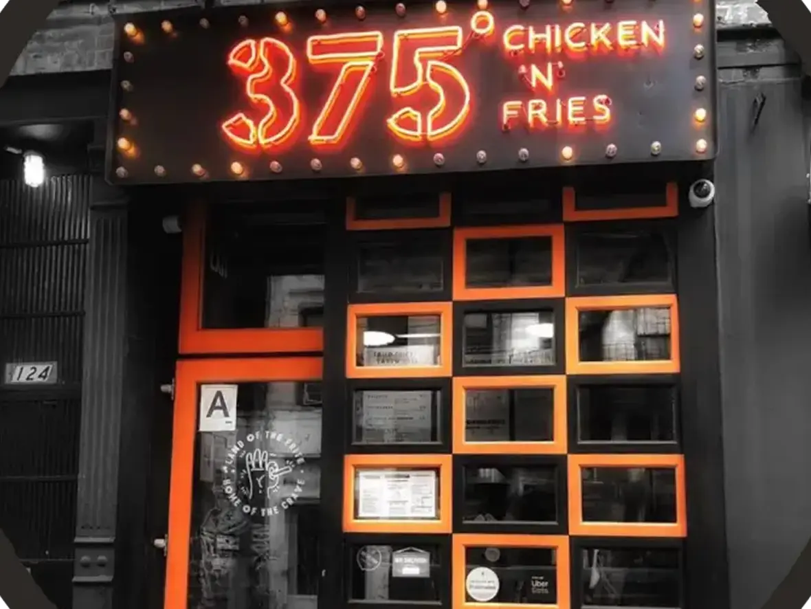 A restaurant with a neon sign that reads 375 chicken n fries.