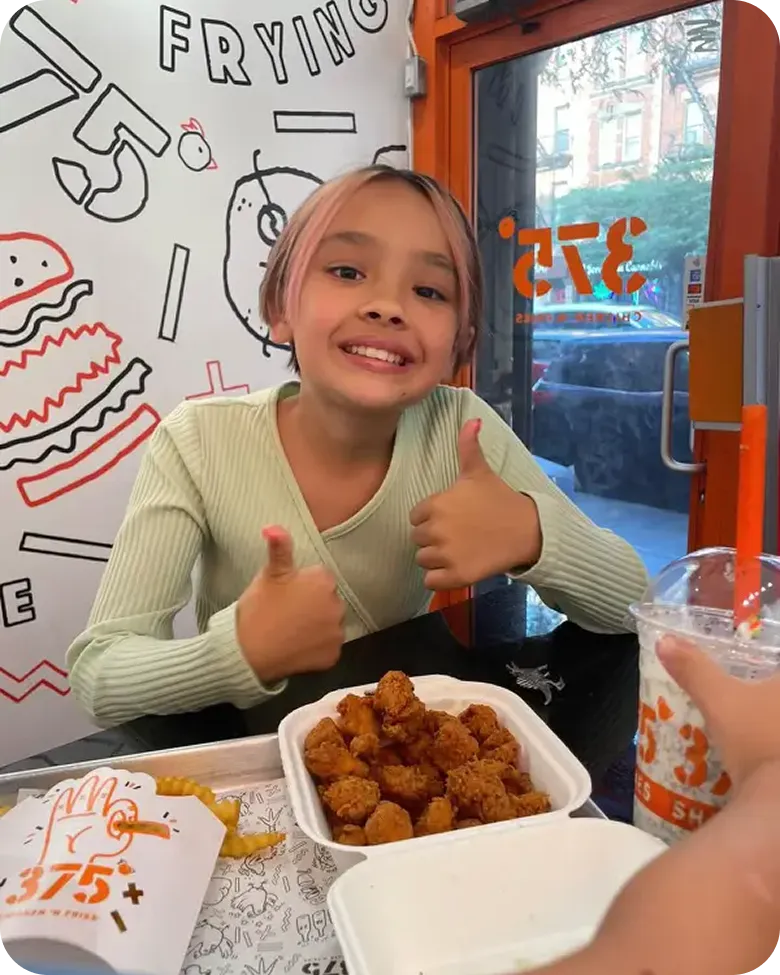 A little girl sitting at a table with a plate of food.