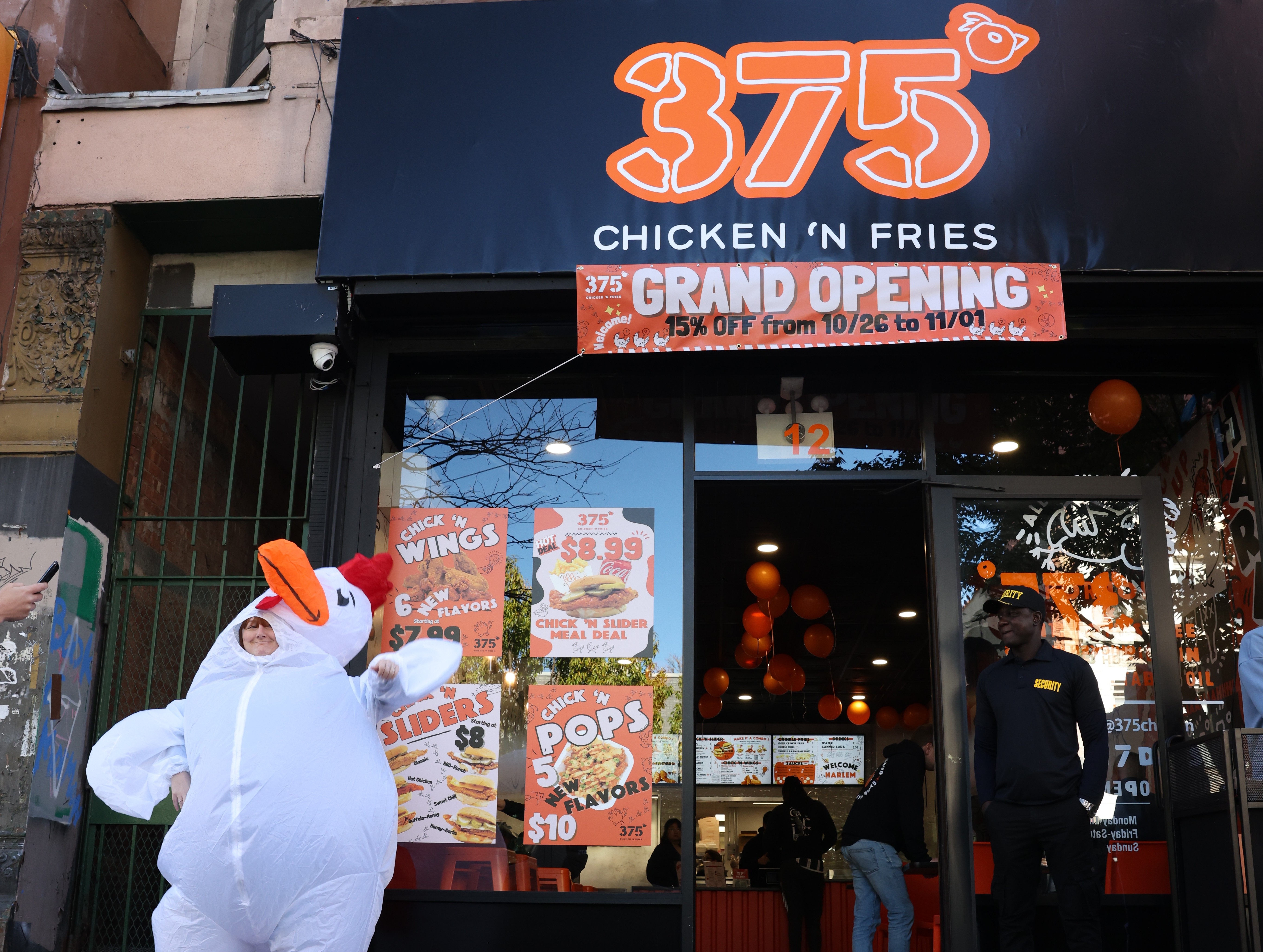 Black storefront with a neon sign displaying the numbers '375' above an entrance featuring a grid of orange-framed windows.