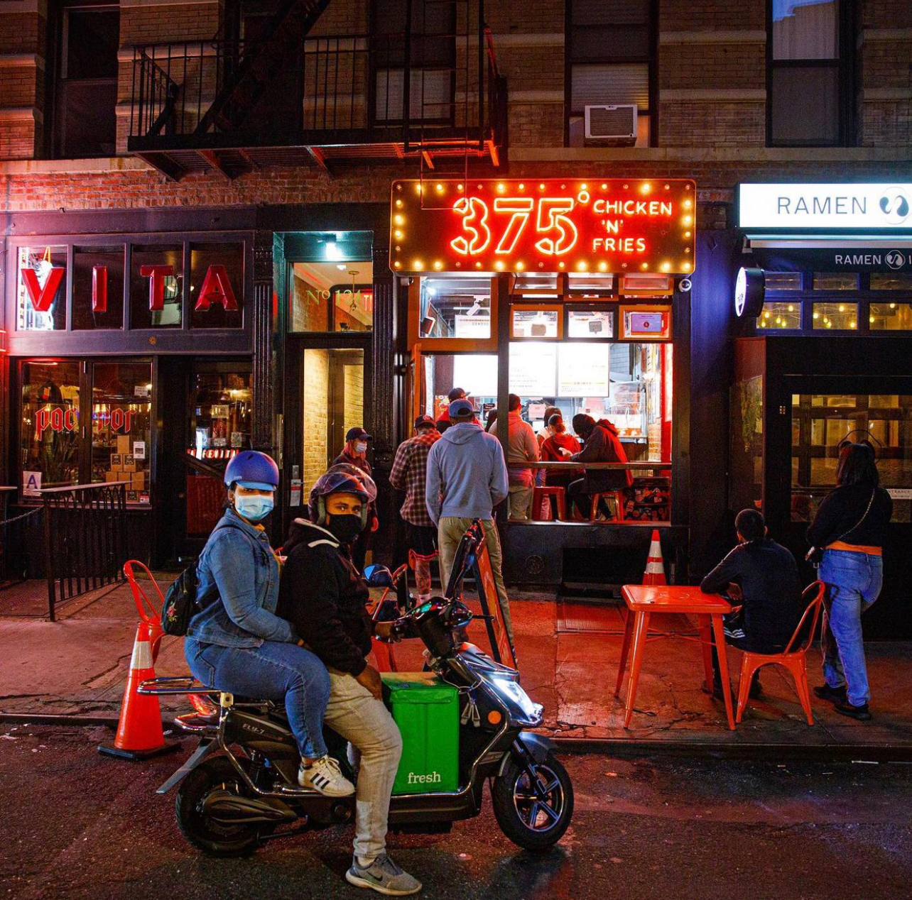 Front view of 375 Chicken 'N Fries restaurant with orange logo and text on black sign and glass windows.