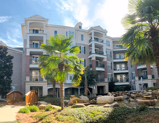 spring harbor senior living apartments among trees and a large pond surrounding by rocks