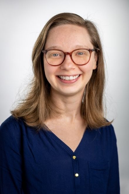 A photo of a blonde woman wearing glasses in a lively restaurant. 