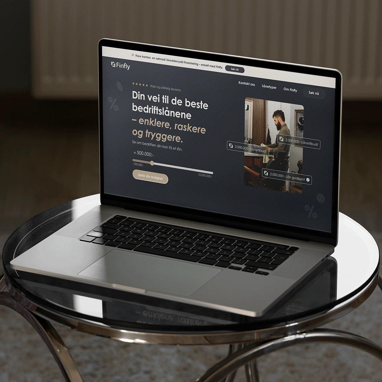 A laptop on round glass table. Displaying a website, the design for Finfly.