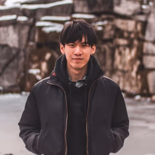 A young man standing in front of a rock formation.