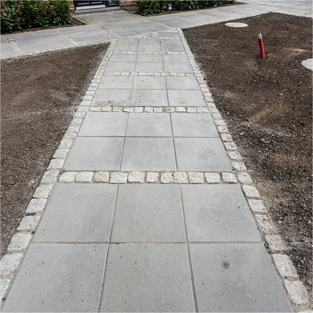 Tæt på flisegang udført i klassisk rådhusbelægning med chaussésten.