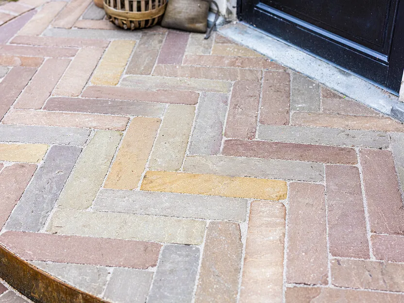 Detalje af brolægning lagt i klassisk sildebensmønster med champagne-farvede sandsten.