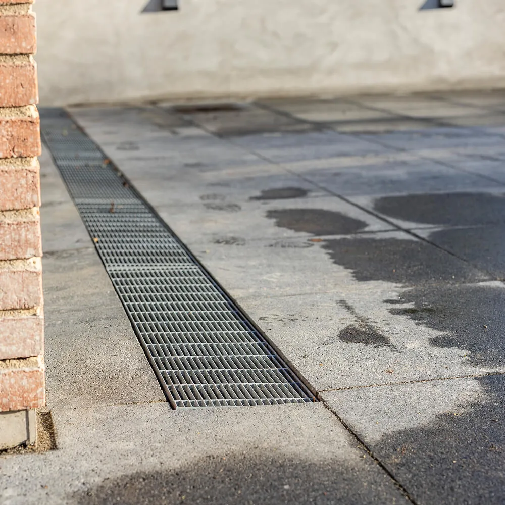 Teknisk detalje af Aquadræn-rende monteret i nyanlagt brolægning.