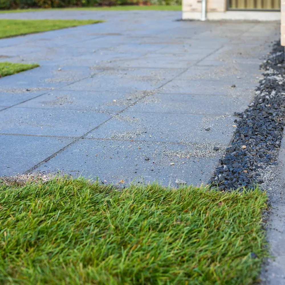 Overgangen mellem de grå fliser, sorte granitskærver og det nyanlagte rullegræs.