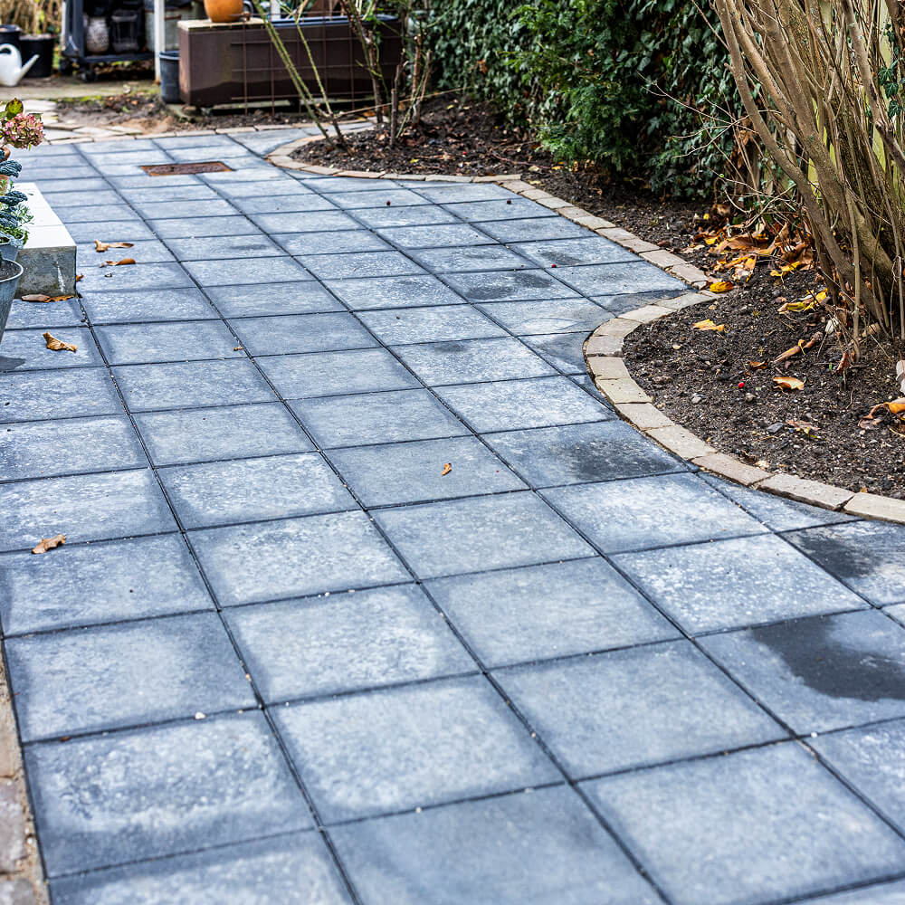 Funktionel og æstetisk brolægning afsluttet mod hæk og bede.