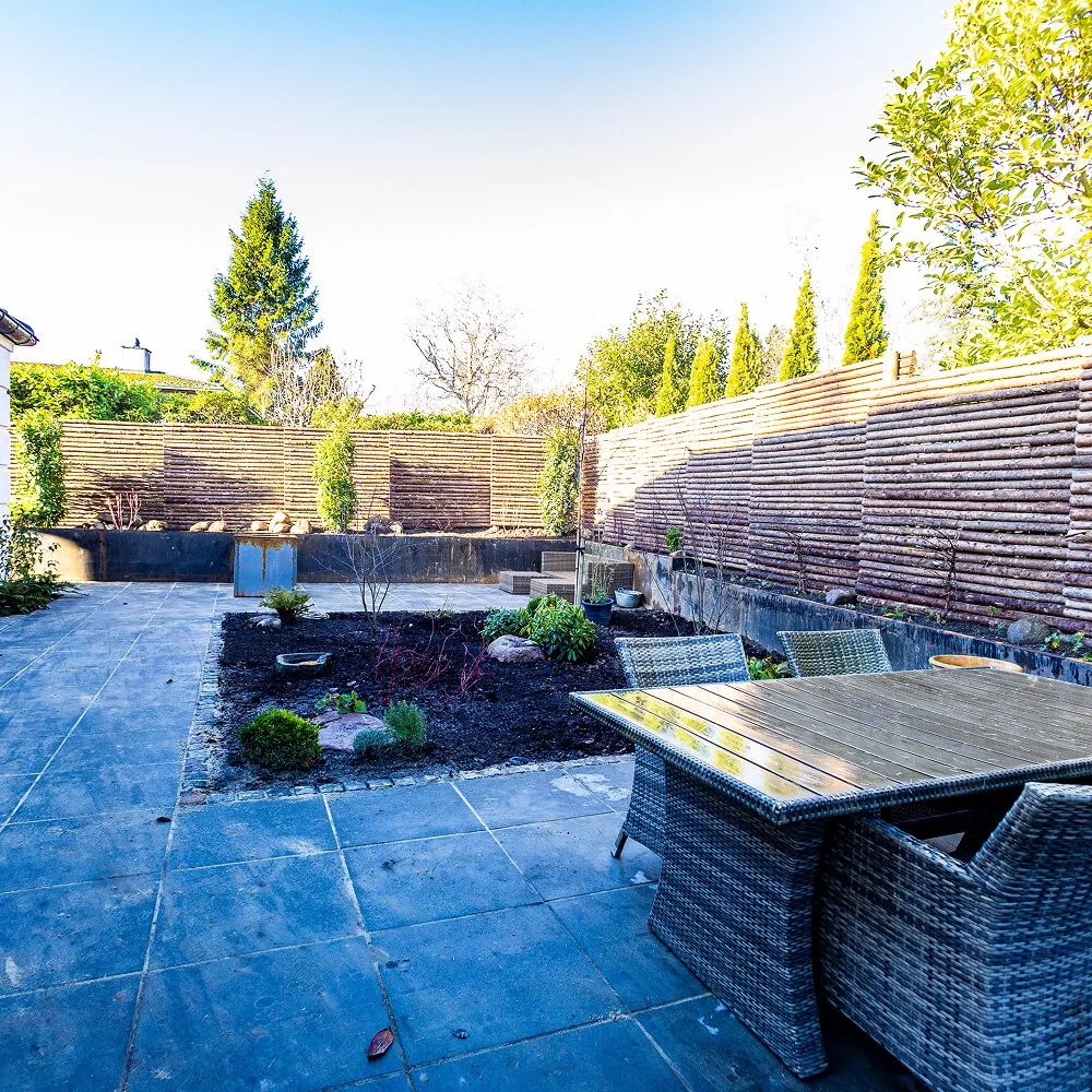 Moderne terrassemiljø med fliser og højbede i Cortenstål.