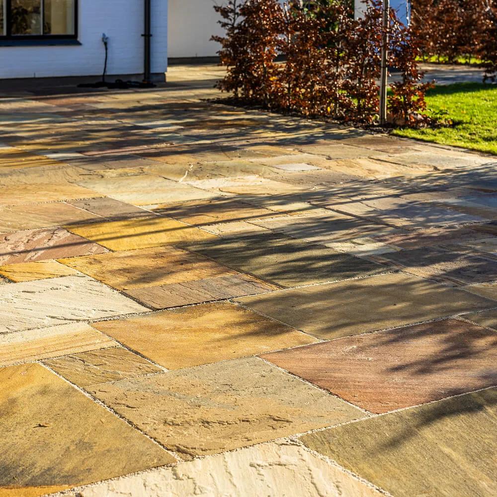 Sollys der fremhæver de varme farver og nuancer i sandstensbelægningen.