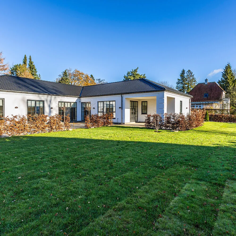 Oversigt over haveanlæg med nyanlagt grøn plæne og moderne bolig.