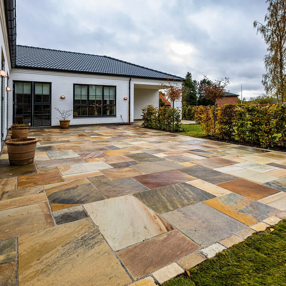 Stor eksklusiv terrasse anlagt med natursten i varierede farvenuancer.