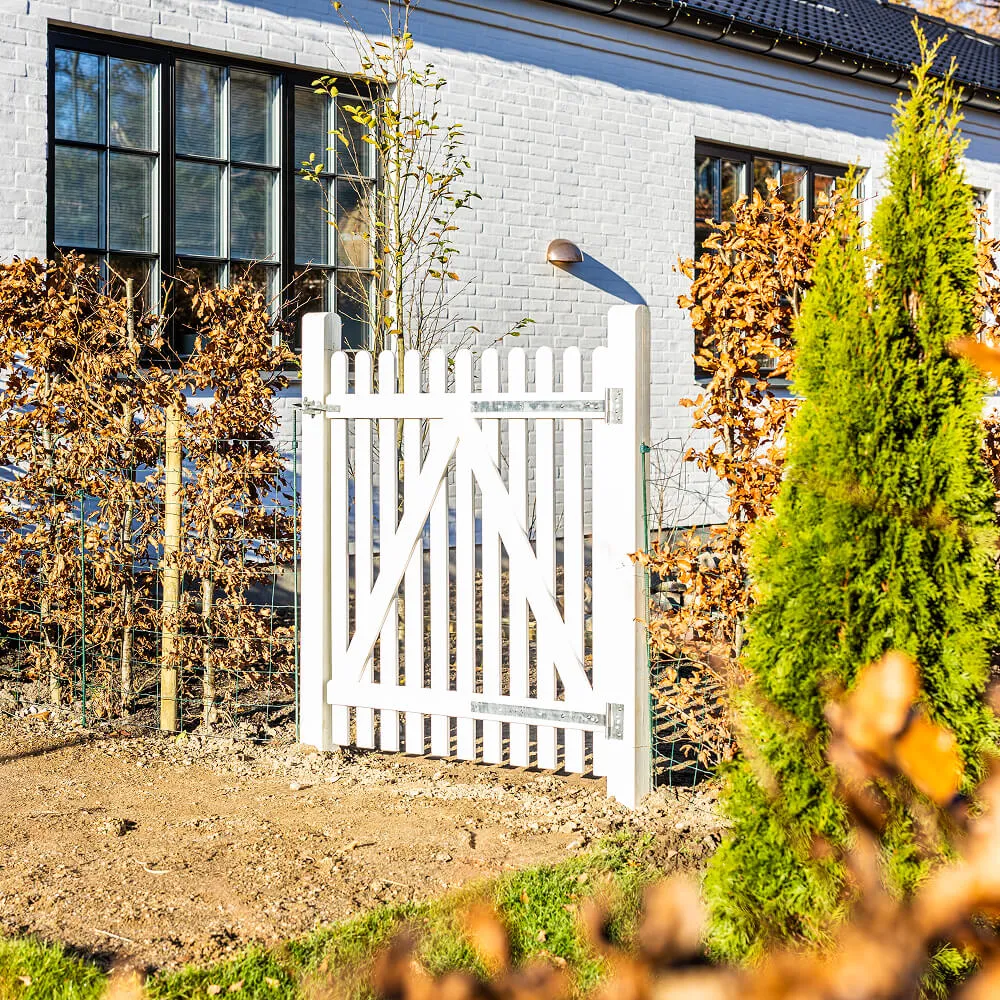 Grøn have afsluttet med klassisk hvidt stakit og bøgehæk.