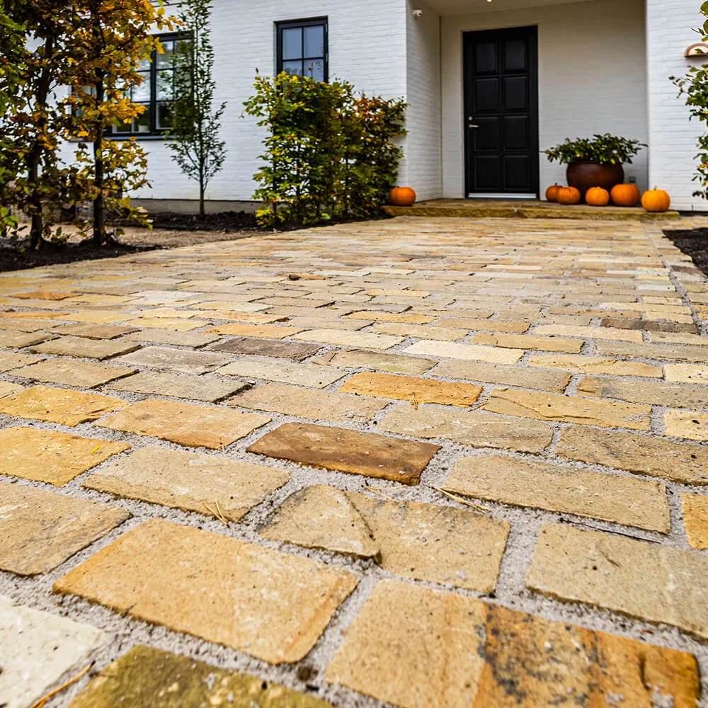 Detaljeret brolægning med varme sandstensnuancer lagt i varierede størrelser.