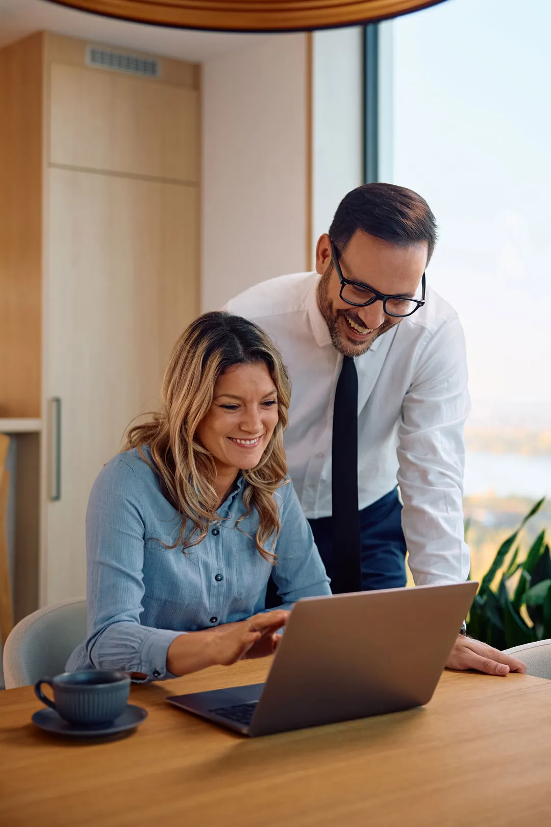 Two brokers smiling at a laptop