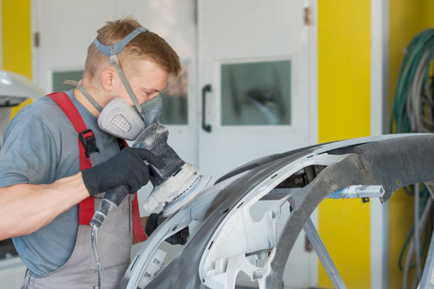 Technician performing professional panel beating and sanding during vehicle collision repair in a Christchurch auto body workshop.