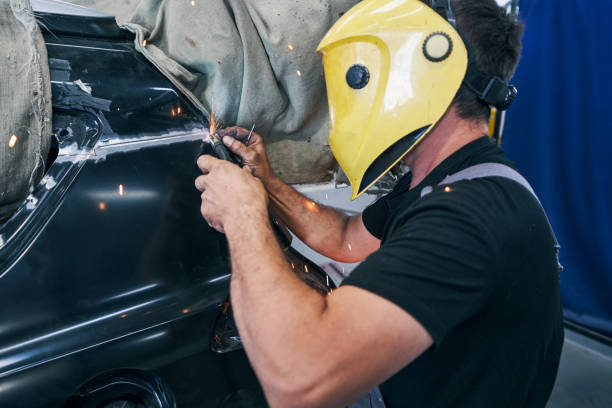 Technician performing car collision repair and panel beating on a damaged vehicle in a Christchurch auto body workshop.