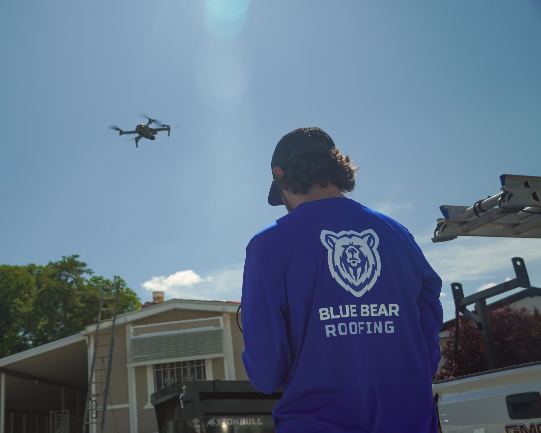 A Blue Bear Roofing Drone pilot flying a drone and taking photos of a roof replacement