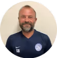 Ein männlicher Fußball Trainer auf einem Spielfeld mit seinen Spielern