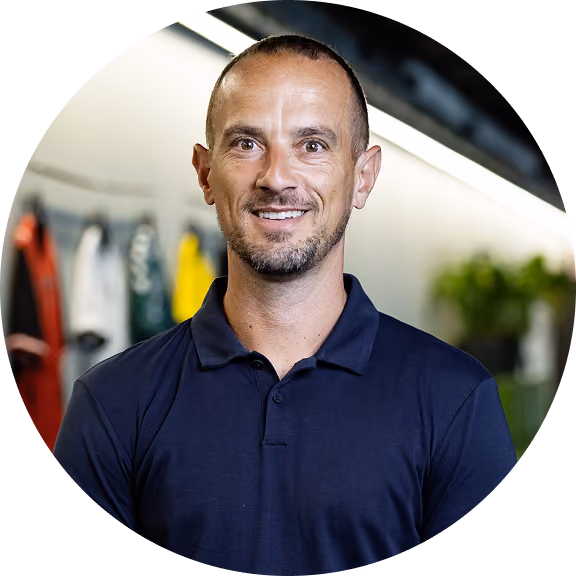 Smiling man with a shaved head wearing a navy polo shirt