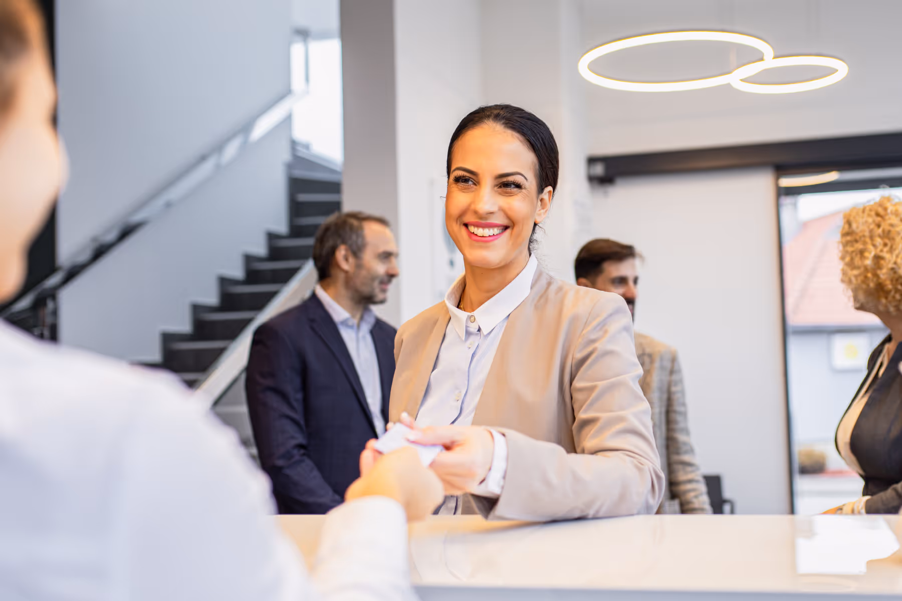 Donna sorridente accolta a un desk di ingresso