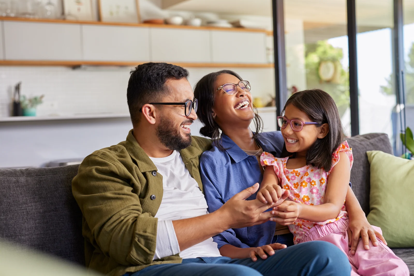 Family laughing together on a sofa at home.