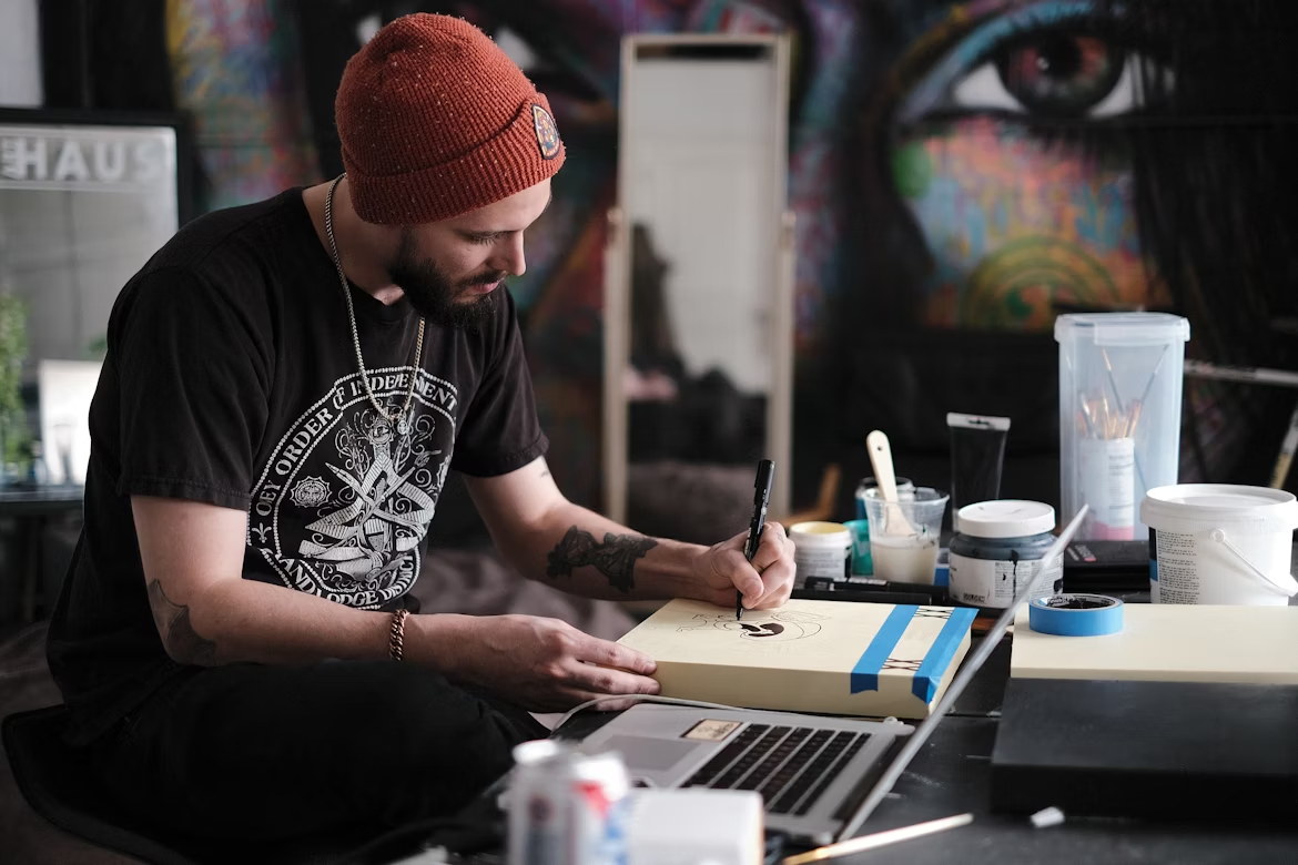 An artist painting next to the laptop