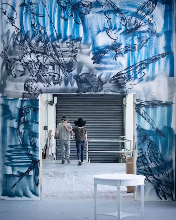 Photograph of David Bromley and Yuge Bromley walking through a painted doorway by David Bromley in West Village Brisbane