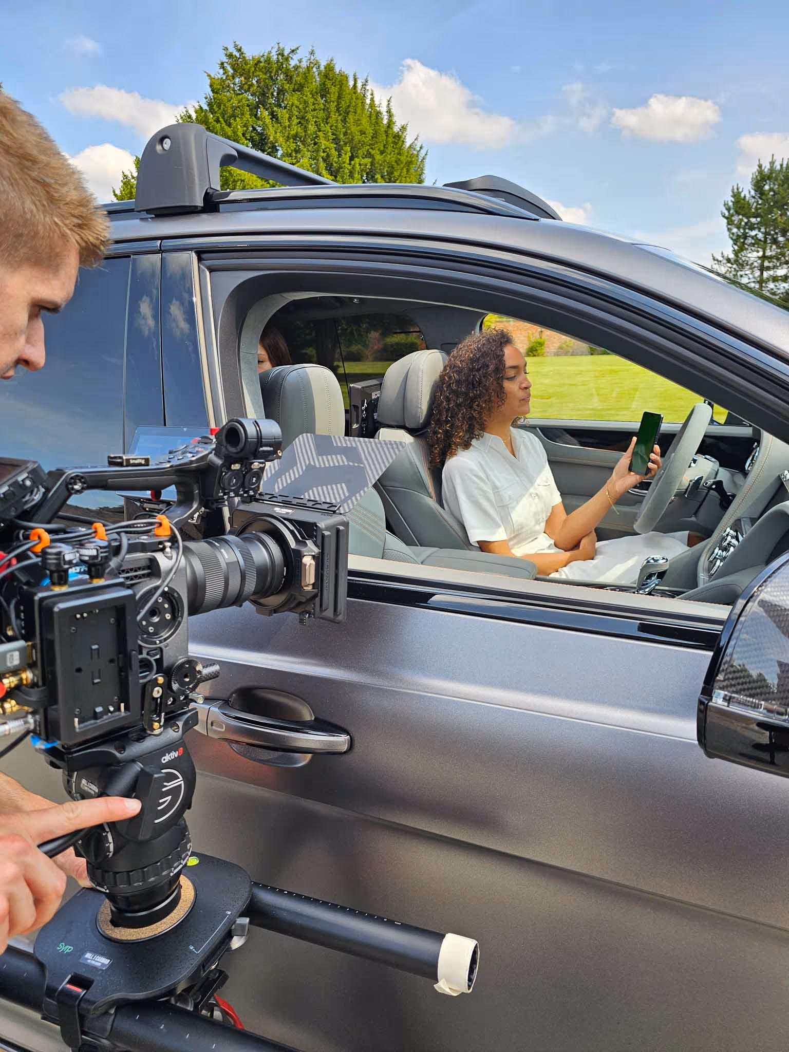Person filming beside a car.