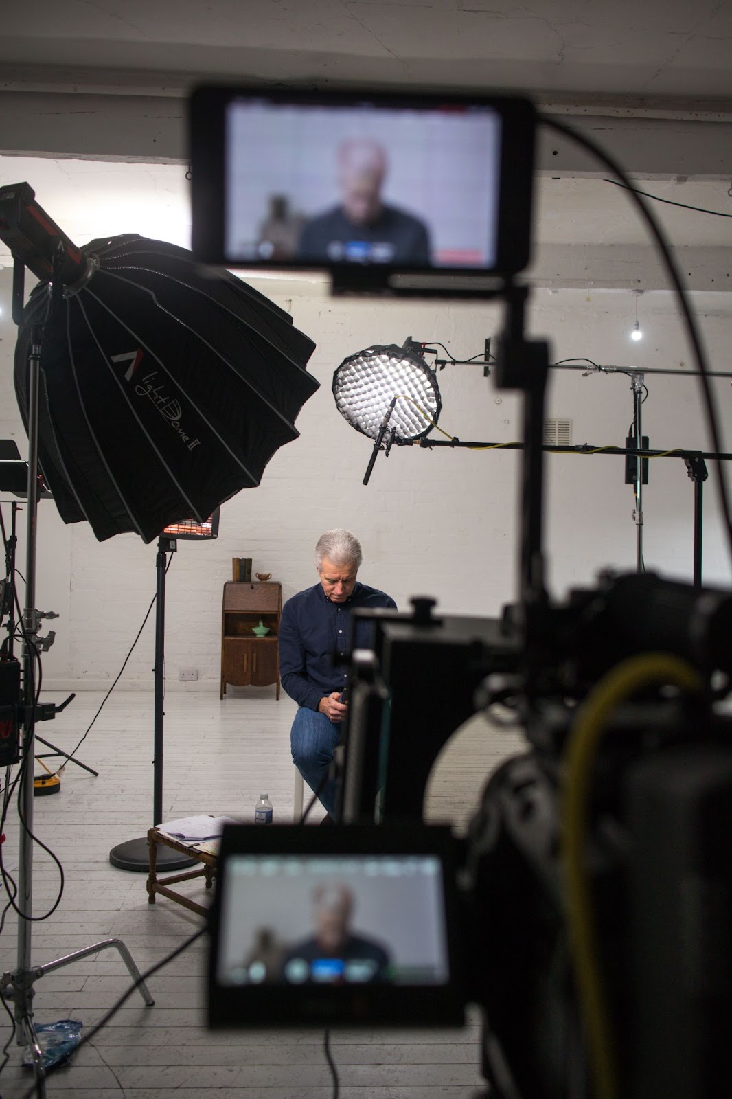 Camera recording man in studio with lighting setup