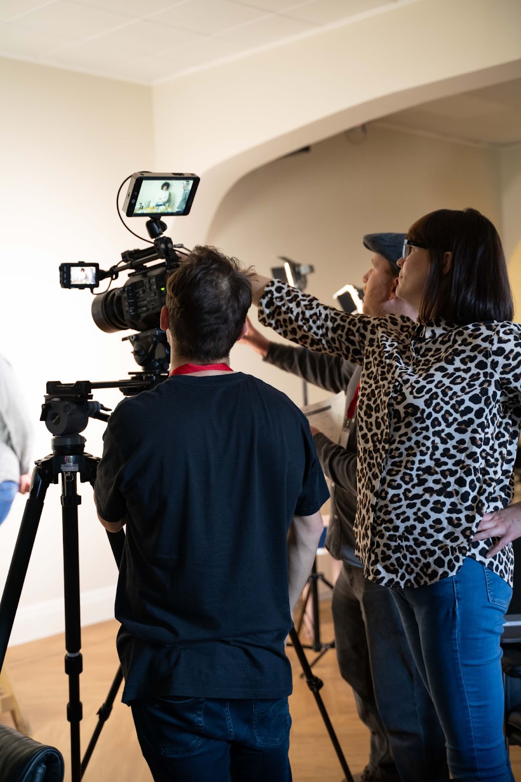 Video crew adjusting camera on tripod indoors