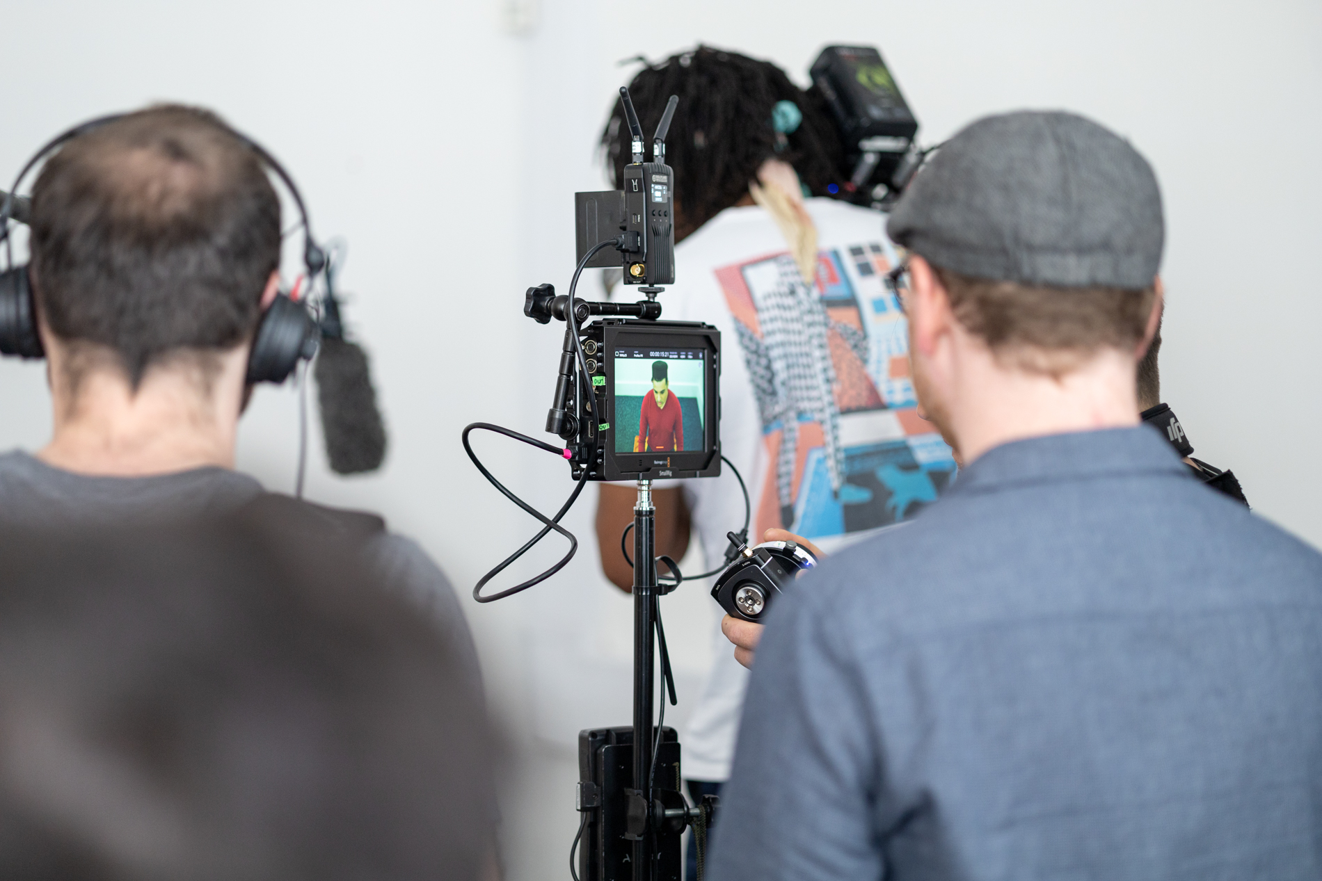 Cameraman filming indoors with two people on set.