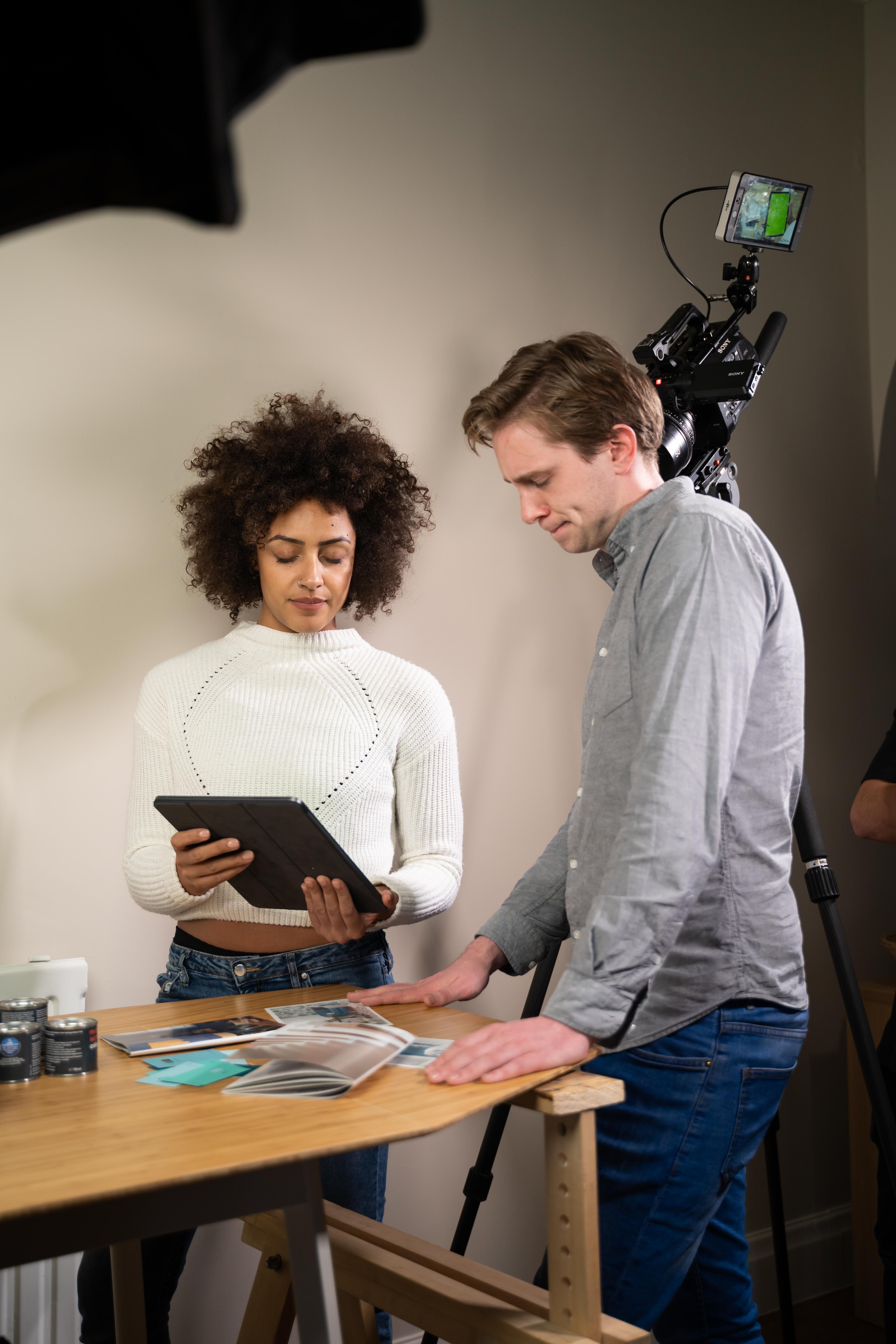 Team members reviewing project notes on tablet during video shoot.