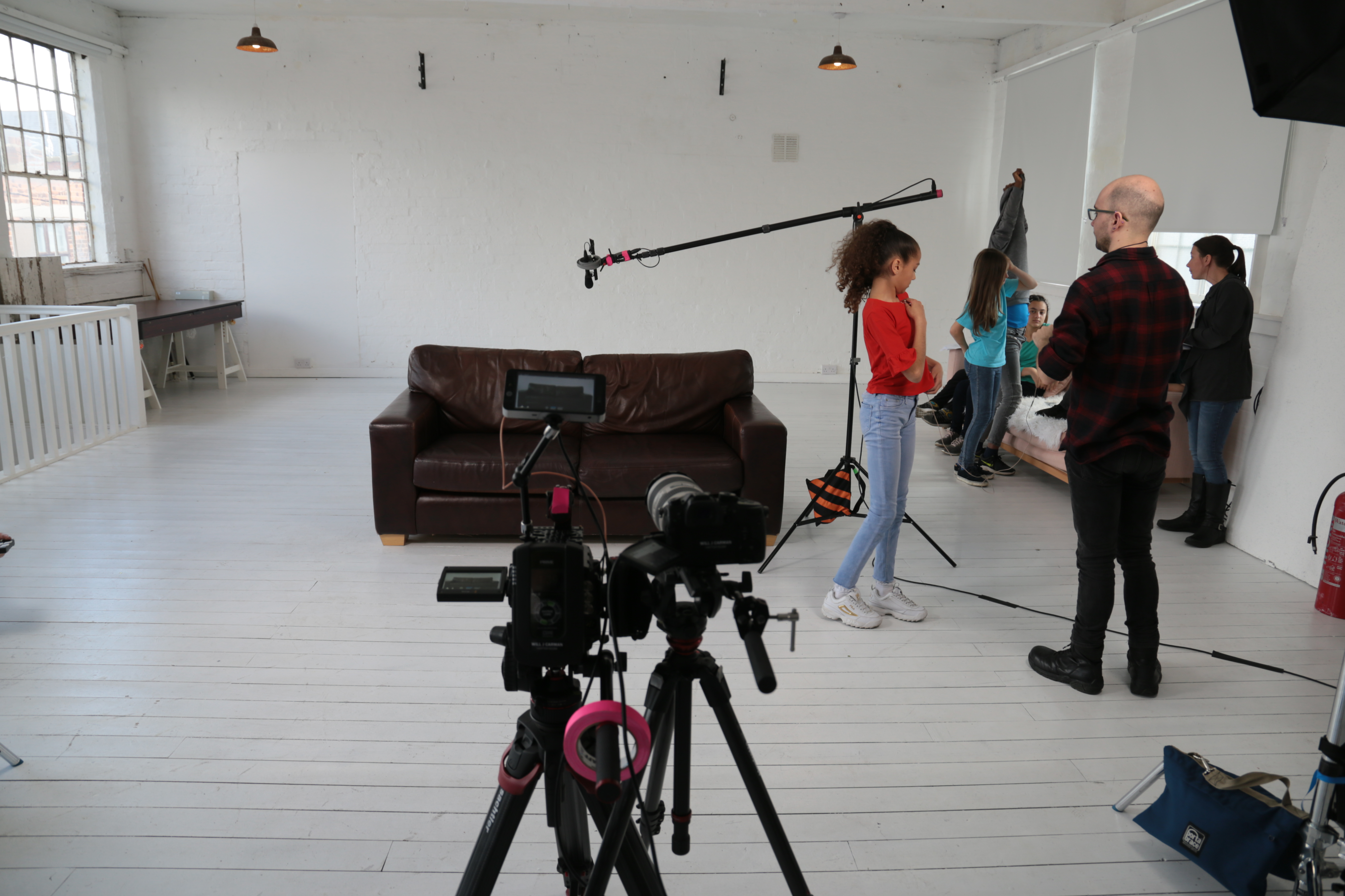 Film crew setting up camera and equipment in studio.