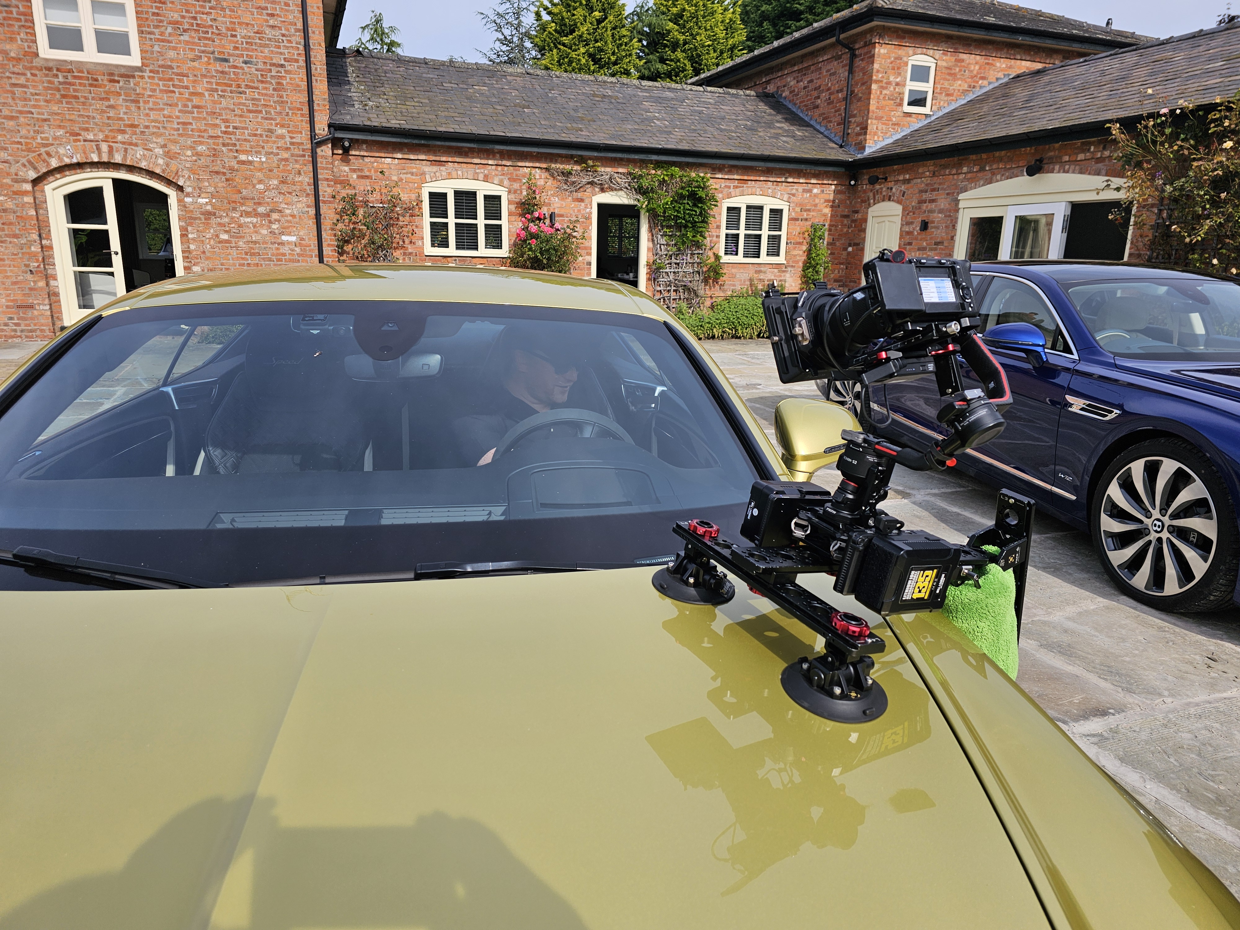 Professional video camera rig mounted on a yellow car for filming.