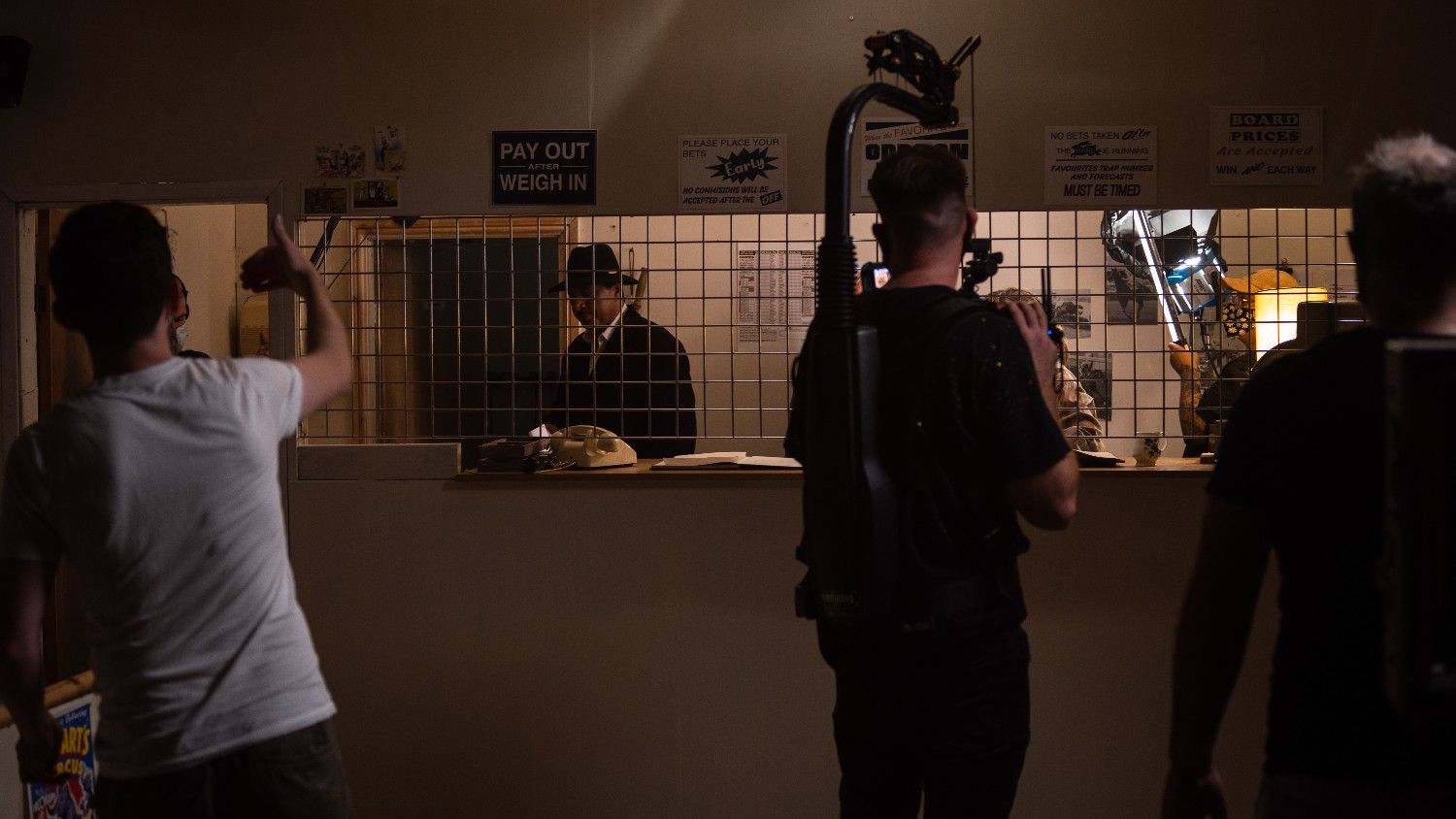 Film crew recording a scene inside a dimly lit room.